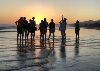 Group standing at beach at sunset
